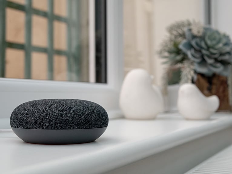 Grey smart speaker on white window ledge
