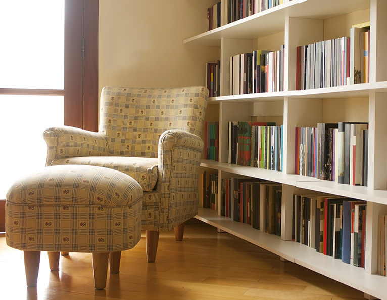 Reading chair and foot stool in room with many bookshelves