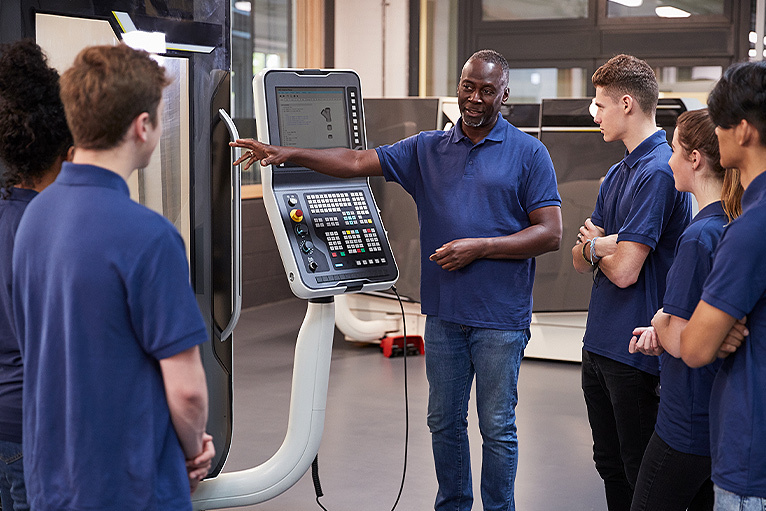 Tradesman teaching a group of apprentices how to use equipment
