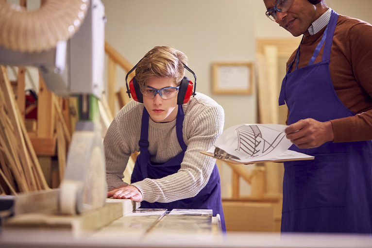 Assessor watching an apprentice carpenter complete a task