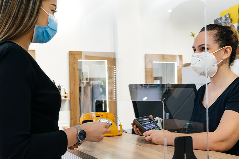 Coronavirus - customer speaking to a receptionist behind a plastic partition
