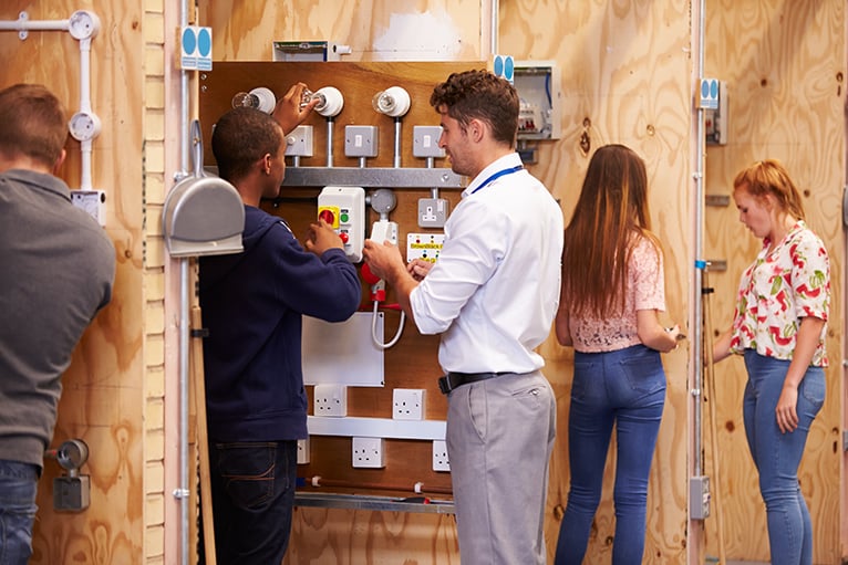 Trades training: Teacher helping trainee electricians