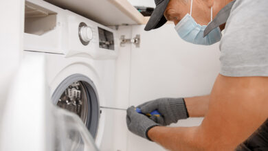 Tradesperson fixing washing machine whilst wearing mask