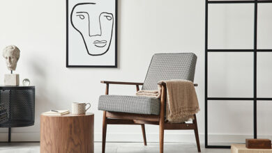 Scandinavian style living room with design armchair, black mock up poster frame, commode, wooden stool, book, decoration, loft wall and personal accessories
