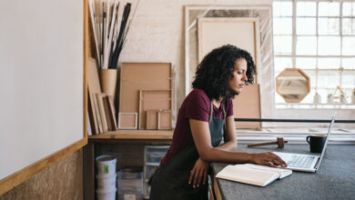 Carpenter leaning on a workbench and looking at laptop