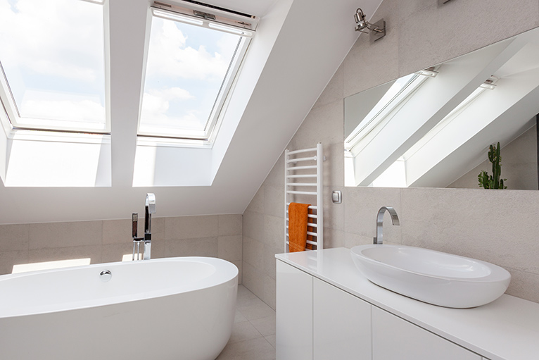 Skylight windows letting light into a white-painted, fresh modern bathroom.
