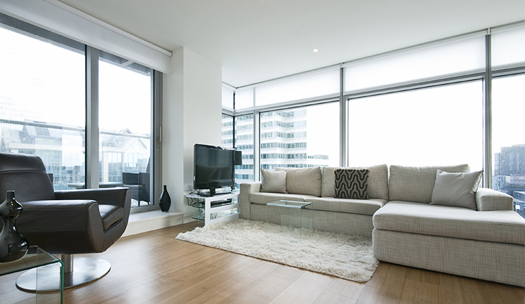 Tall and broad window walls, surrounding the living area of a flat in a high-rise building.