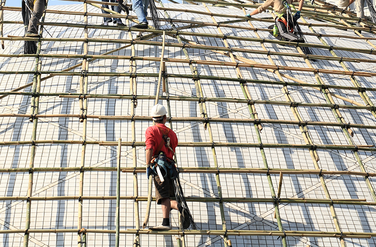 Tradesmen working on the roof of a building being constructed with bamboo.
