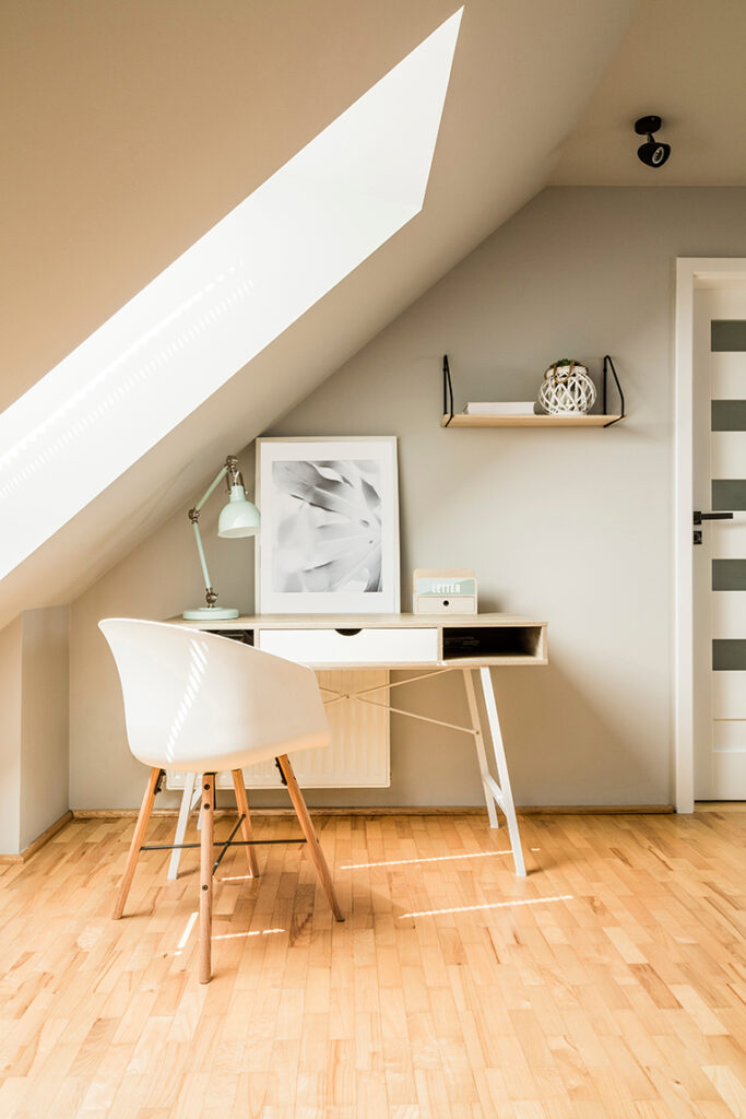 White office desk and chair set in loft room with bight decor and lighting.