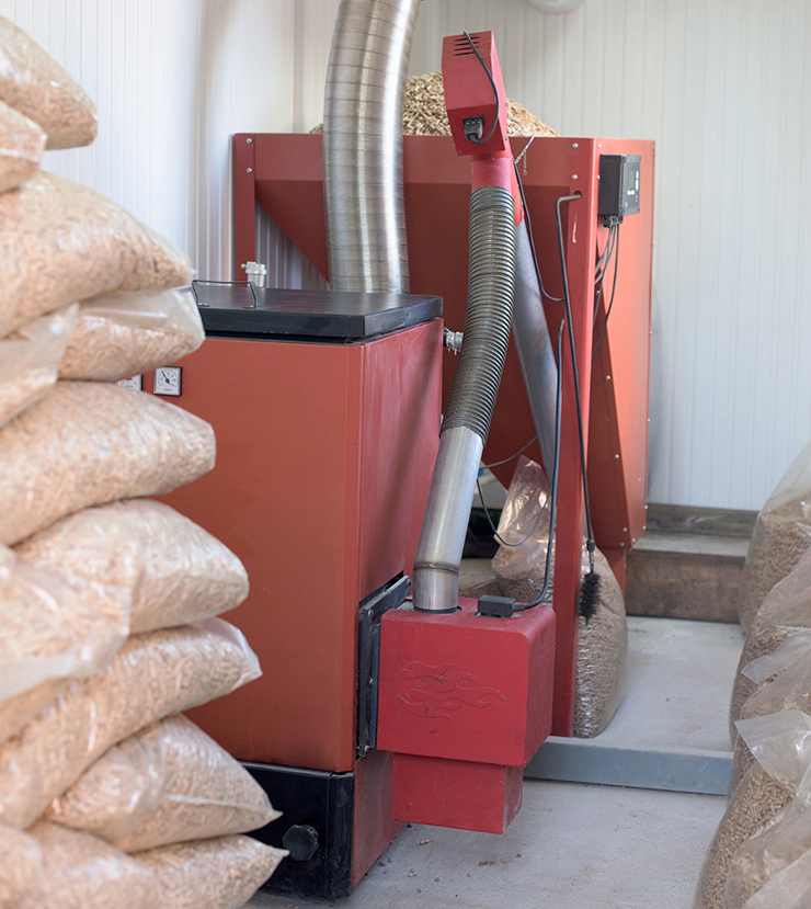 Picture of a biomass boiler with bags of wood chip fuel beside it
