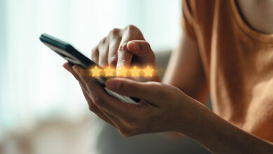 Picture of a close up of hands holding a phone with five stars illustrated to show rating