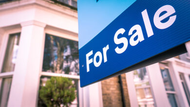 Picture of a for sale sign on a street outside a home