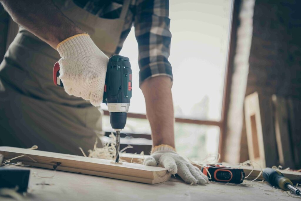 Picture of a builder using a drill to drill into a piece of wood