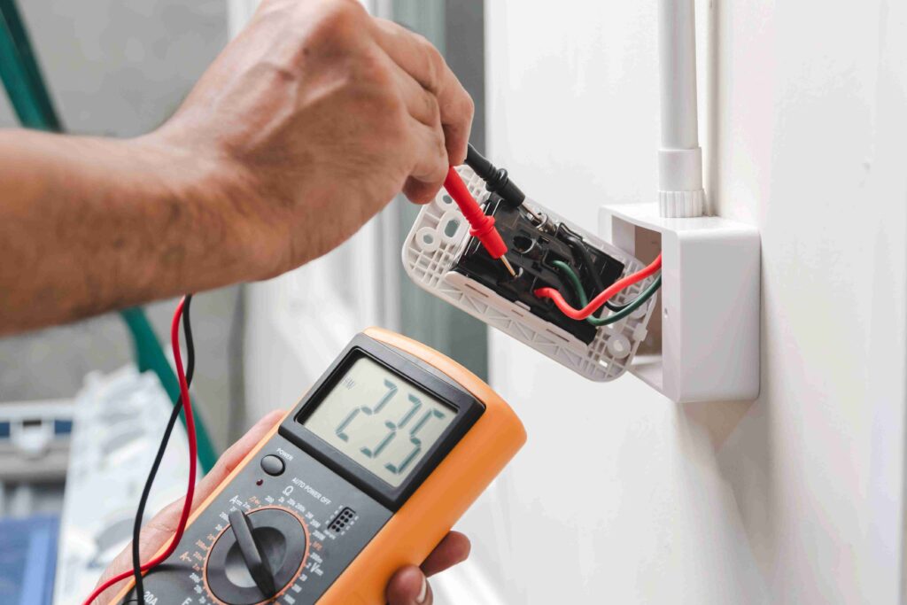 Picture of a pair of hands installing and testing electrics in a socket