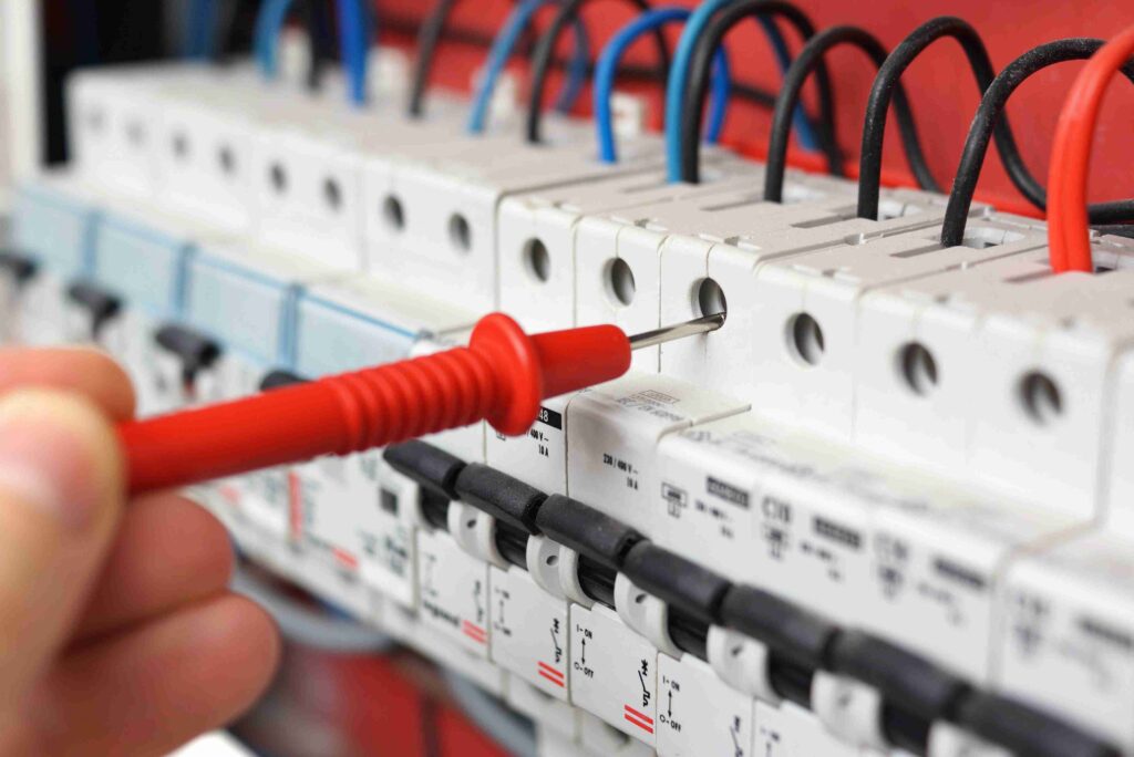 A hand holding tools to test electrical switch board