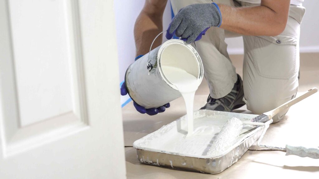 Picture of a painter and decorator pouring white paint into a tray