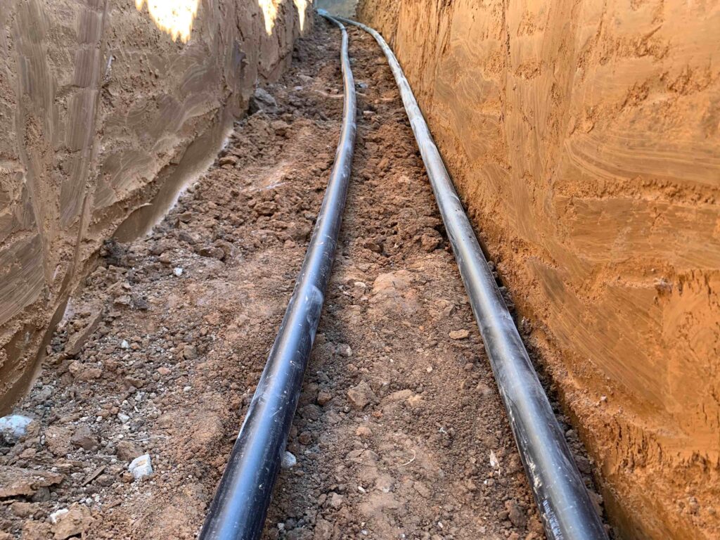 Picture of a ground source heat pump being installed with a long geothermal ground loop in a dug out trench