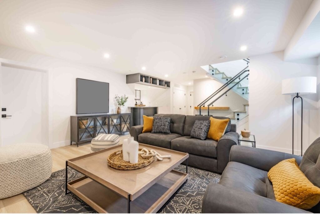 Picture of a basement converted into a living room with grey sofas and a glass panel staircase